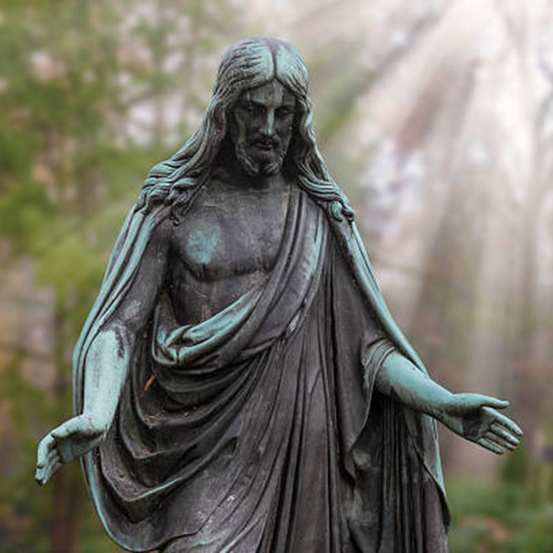 Jesuo statuo sur tombejo;lumradioj en la fono